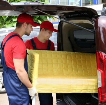Günstig umziehen in Grevenbroich Günstig umziehen in Grevenbroich: Umzugshelfer laden ein gelbes Sofa in einen Transporter