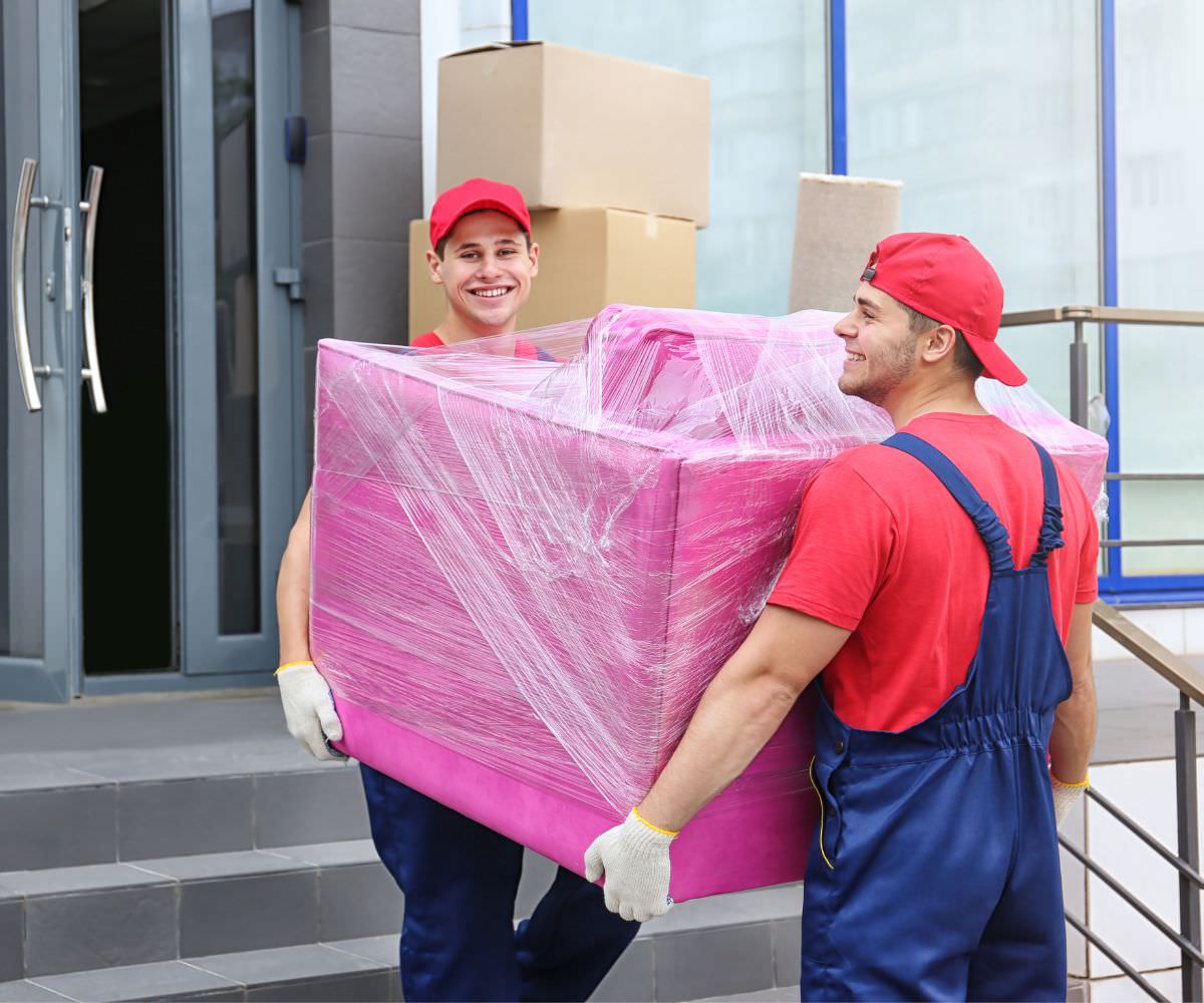 Zwei Umzugshelfer tragen ein in Folie gepacktes Möbelstück – Umzugsunternehmen Grevenbroich