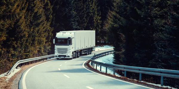 Klaviertransport Grevenbroich: Lkw fährt auf einer kurvigen Straße durch den Wald