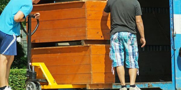 Möbellift Grevenbroich: Zwei Helfer tragen einen Holzschrank aus einem Lkw